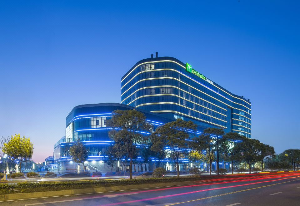 The building where a hotel is located is illuminated by neon lights at night at Holiday Inn Express Hangzhou East Station