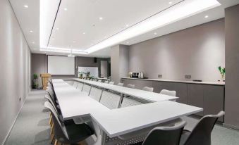 There is a large meeting room with long tables and chairs located next to the conference table at Home Inn (Shanghai North Bund Dalian Road Subway Station)