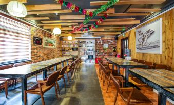 The restaurant features long tables and chairs, as well as wood paneling on the walls and ceiling tiles at Maker Hotel