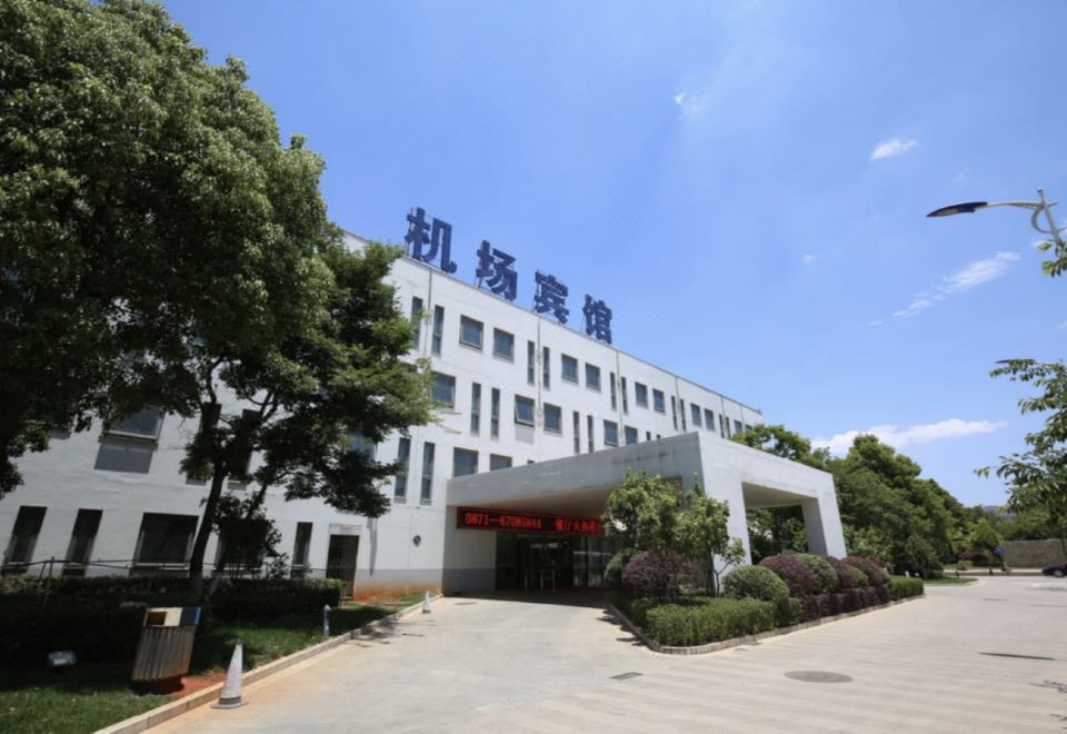 "a large white building with a blue sign that says "" china university "" on it , surrounded by trees and grass" at Airport Hotel
