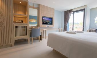 a hotel room with a king - sized bed , a flat - screen tv mounted on the wall , and a desk at Beyond Patong