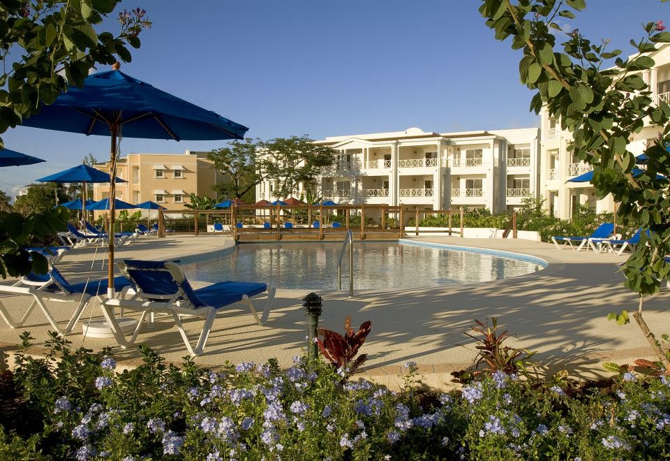 a swimming pool surrounded by lounge chairs and umbrellas in front of a hotel building at Beach View Hotel