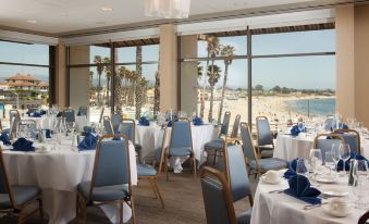 a large , well - decorated dining room with multiple tables and chairs set up for a formal event , overlooking a body of water at Dream Inn Santa Cruz