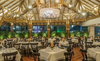 a well - lit restaurant with numerous dining tables and chairs arranged for guests to enjoy a meal at Hotel Campestre las Camelias