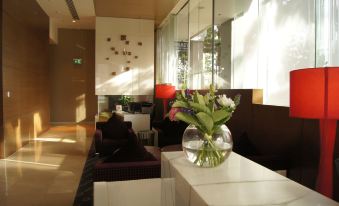 a modern living room with large windows , white furniture , and a vase of flowers on the coffee table at Pullman at Sydney Olympic Park
