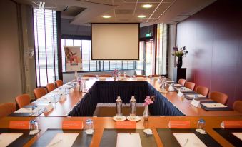 a conference room set up for a meeting , with multiple chairs arranged in a semicircle around a table at Leonardo Hotel Lelystad City Center