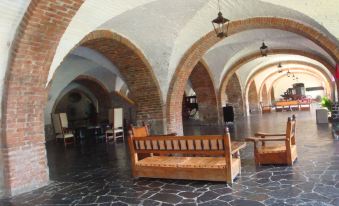 an indoor courtyard with stone flooring , arches , and wooden benches , creating a sense of historical and architectural beauty at Hotel Hacienda Vista Hermosa