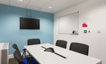 a conference room with a white table , black chairs , and a whiteboard , along with a tv mounted on the wall at Super 8 by Wyndham Chester East