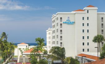 a large white hotel building with blue and orange accents , situated near the ocean and surrounded by palm trees at Aquarius Vacation Club at Dorado del Mar