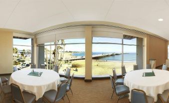 a dining room with a large window overlooking the ocean , featuring a table and chairs at Dream Inn Santa Cruz