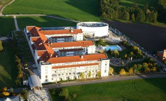 aerial view of a large white building surrounded by green grass and trees , with a swimming pool in the background at The Monarch Hotel