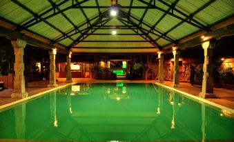 an indoor swimming pool with a green color scheme , surrounded by pillars and a gazebo at Aalankrita Resort and Convention