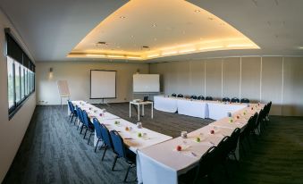 a large conference room set up for a meeting , with multiple tables and chairs arranged in an orderly fashion at Alpha Hotel Eastern Creek