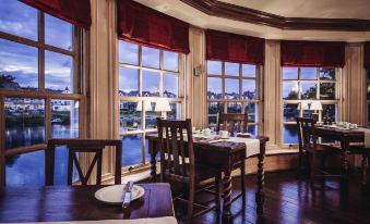 a dining room with a wooden table , chairs , and a window overlooking a body of water at Small Luxury Hotels of the World - the Mitre Hampton Court