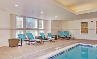 a hotel room with a large window , blue chairs and tables , and a swimming pool at Residence Inn by Marriott Princeton at Carnegie Center