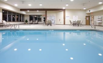 an indoor swimming pool with a blue and white striped floor , surrounded by chairs and tables at Country Inn & Suites by Radisson, Sidney, NE