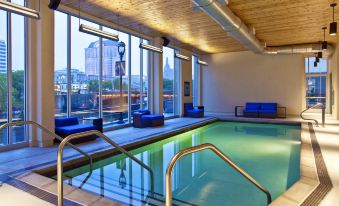 an indoor swimming pool surrounded by large windows , allowing natural light to fill the space at Aloft Milwaukee Downtown