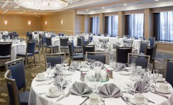 a large dining room with numerous tables and chairs set up for a formal event , possibly a wedding reception at DoubleTree by Hilton Hotel Syracuse