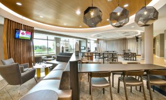 a modern restaurant with a large dining table surrounded by chairs and couches , creating a cozy atmosphere at SpringHill Suites Grand Forks