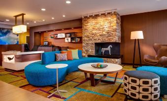 a living room with a blue couch , coffee table , and a fireplace in the background at Comfort Suites Canton