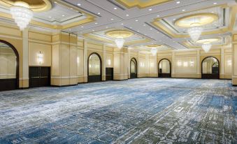 a large , empty conference room with a blue and white carpet , multiple chandeliers , and multiple doors at Delta Hotels Woodbridge