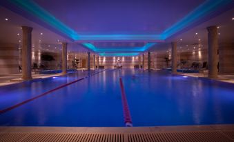 a long , rectangular swimming pool with blue lights illuminating the area and a red lane marking at Lion Quays Resort