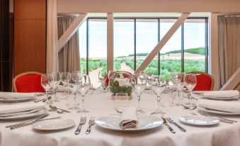 a table is set with white linens , silverware , and wine glasses in front of a window overlooking a landscape at Exe Layos Golf