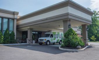 a green and white van is parked in front of a building , possibly a hotel at Hotel Mtk Mount Kisco