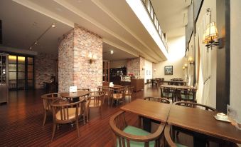 a modern restaurant with wooden tables and chairs , a brick wall , and large windows on the second floor at La Vista Hakodate Bay