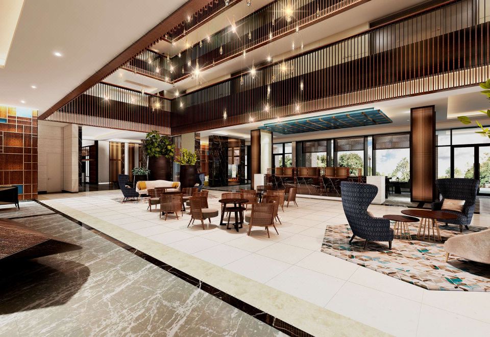 a large , well - lit lobby with multiple seating areas , including couches and chairs , surrounded by wooden flooring and a carpeted floor at Gran Melia Arusha