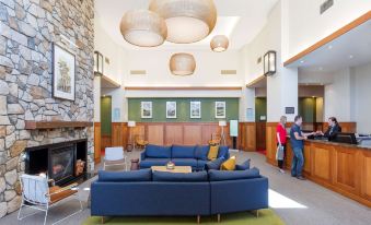 a large , modern living room with blue couches , wooden walls , and a fireplace , as well as several people in the room at Yarra Valley Lodge, an EVT Hotel