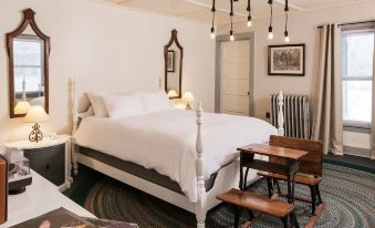 a white bed with a headboard and footboard is in a room with a bed , nightstands , and a chair at The Deers Head Inn Tavern