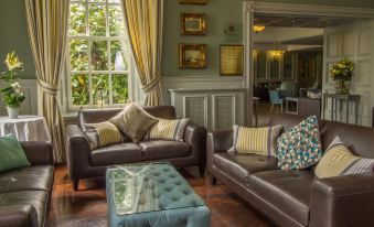 a cozy living room with two brown leather couches and a large window , creating a warm and inviting atmosphere at Bunratty Castle Hotel