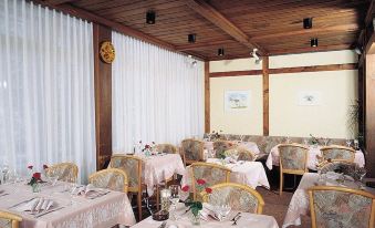 a restaurant with wooden tables and chairs , set with white tablecloths and wine glasses , under a wooden ceiling at Hotel Residence