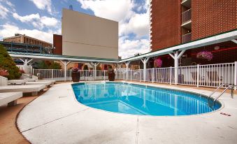 a large outdoor pool surrounded by a hotel building , with people enjoying their time in the pool area at Best Western Plus Wilkes Barre Center City