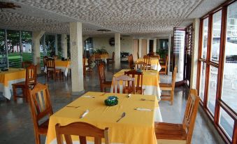 a large dining room with multiple tables and chairs , some of which are covered with yellow tablecloths at Hotel Laguna Bacalar