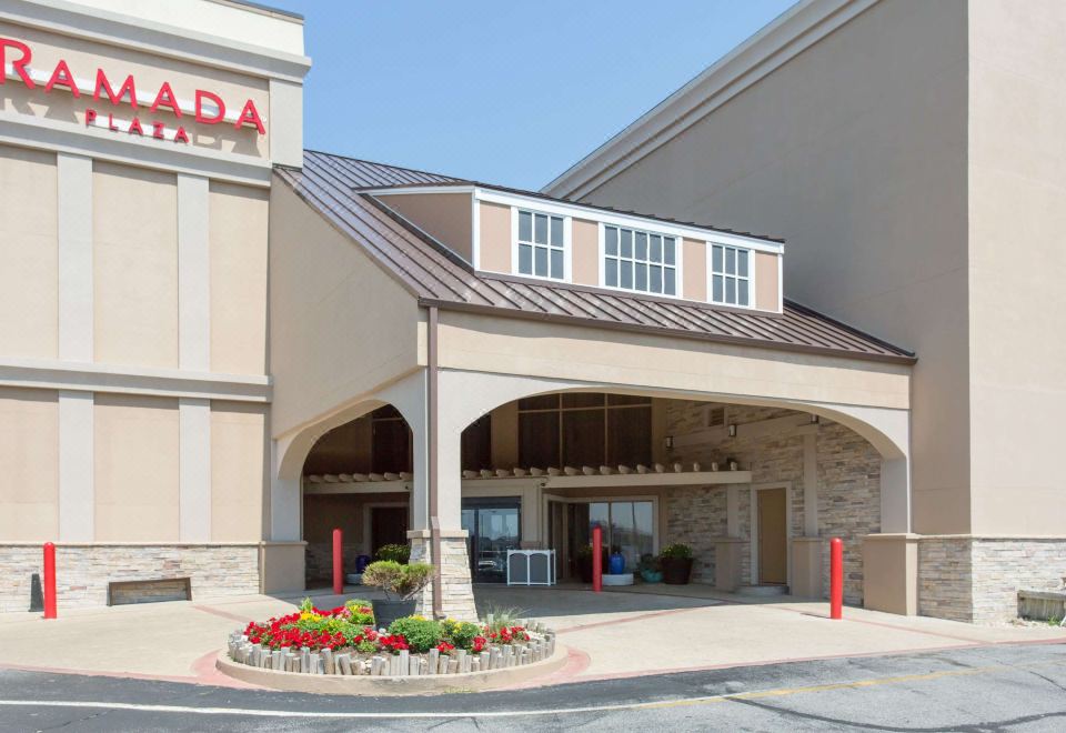 "a large building with a covered entrance and the word "" pasadena "" on the front , surrounded by greenery and flowers" at Ramada Plaza by Wyndham Nags Head Oceanfront