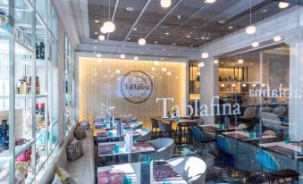 "a modern restaurant with a large glass window , white table and chairs , and the words "" tabllanna "" on the wall" at NH Madrid Nacional