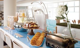 a dining table with a variety of food items , including waffles , ice cream cones , and other snacks at Novotel Dijon Sud