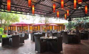 a well - lit outdoor dining area with tables and chairs arranged for guests to enjoy a meal at Aalankrita Resort and Convention