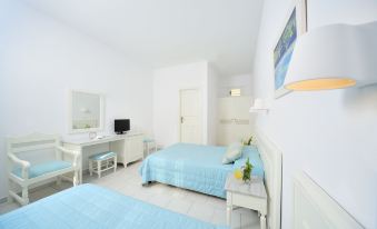 a white bedroom with two beds , one on the left and one on the right side of the room at Mykonos Beach Hotel