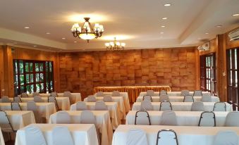 a conference room set up for a meeting , with tables and chairs arranged in rows at Kirirath Resort