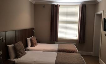 a hotel room with two beds , one on the left and one on the right side of the room at The Buxted Inn