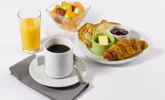 a table is set with a cup of coffee , a croissant , orange juice , and various breakfast items at Campanile Paris Est - Bobigny