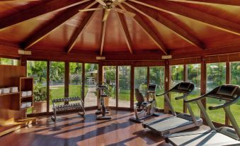 a well - equipped gym with various exercise equipment , including treadmills and stationary bikes , under a wooden roof at Sheraton Mallorca Arabella Golf Hotel