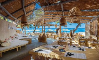 an outdoor dining area at a beachside restaurant , with tables and chairs arranged for guests to enjoy the view of the ocean at Le Meridien Lav Split