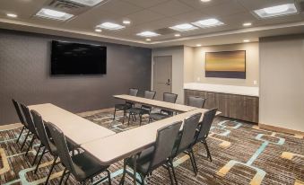 a conference room with multiple tables and chairs , a tv on the wall , and a counter in the background at Residence Inn Rapid City
