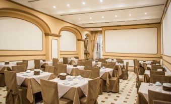 a large dining room with several tables and chairs , all covered in brown tablecloths and ready for guests at Hotel Europa