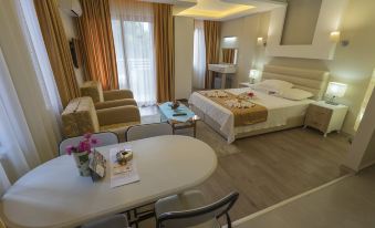 a modern hotel room with a bed , dining table , chairs , and a balcony view of the city at Arya Otel