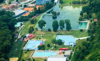 an aerial view of a large swimming pool complex surrounded by greenery and buildings , including a building with a red roof at Hotel Dixon